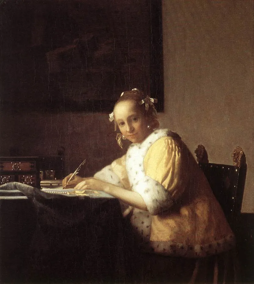 A young woman in a yellow jacket pauses while writing a letter, looking up from her desk